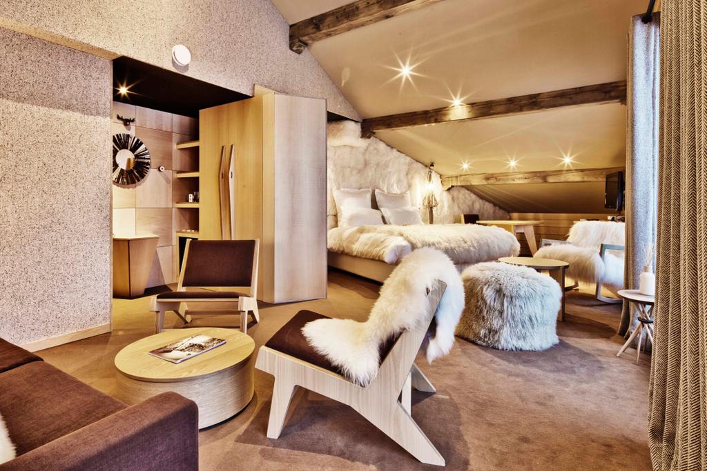 An Altapura room with a bed draped in fur throws and armchairs in warm tones