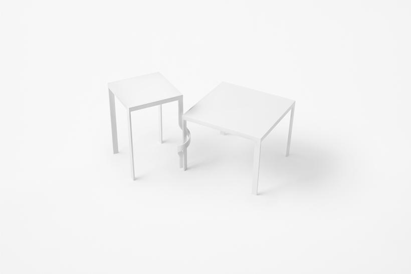 Two slender white tables joined by a twisted leg