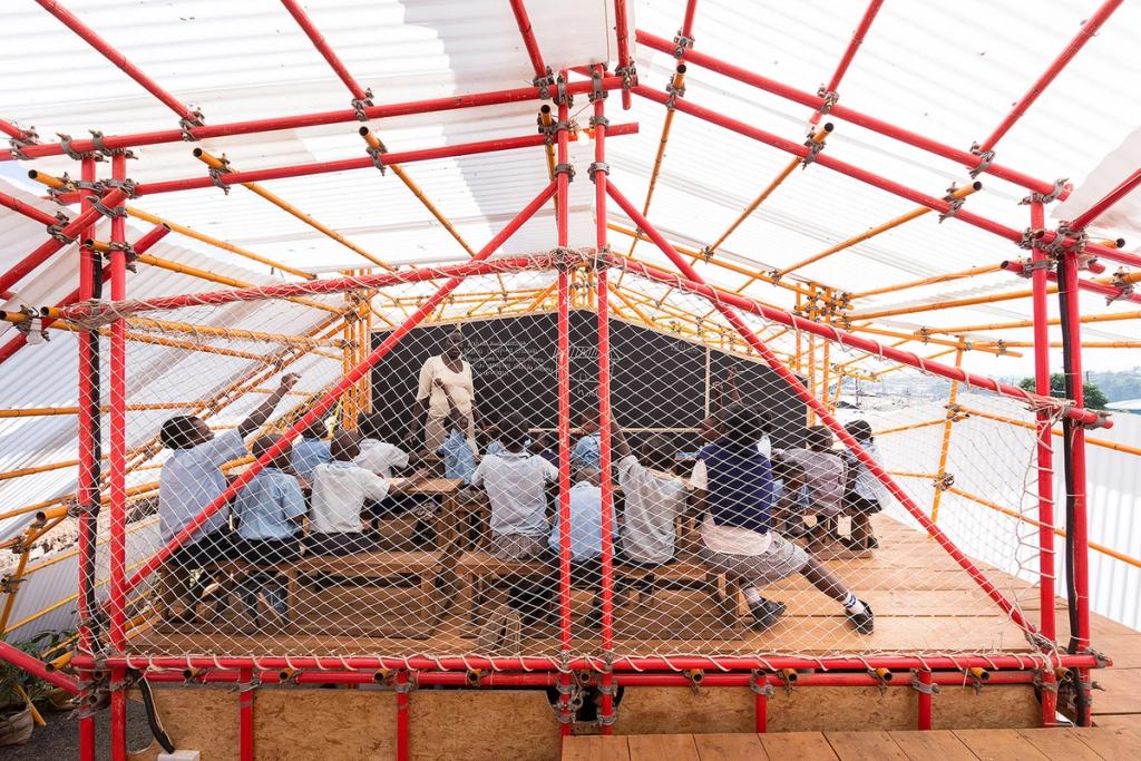 Students in a lesson beneath the red-and-yellow tubular frame with its protective netting at Kibera School