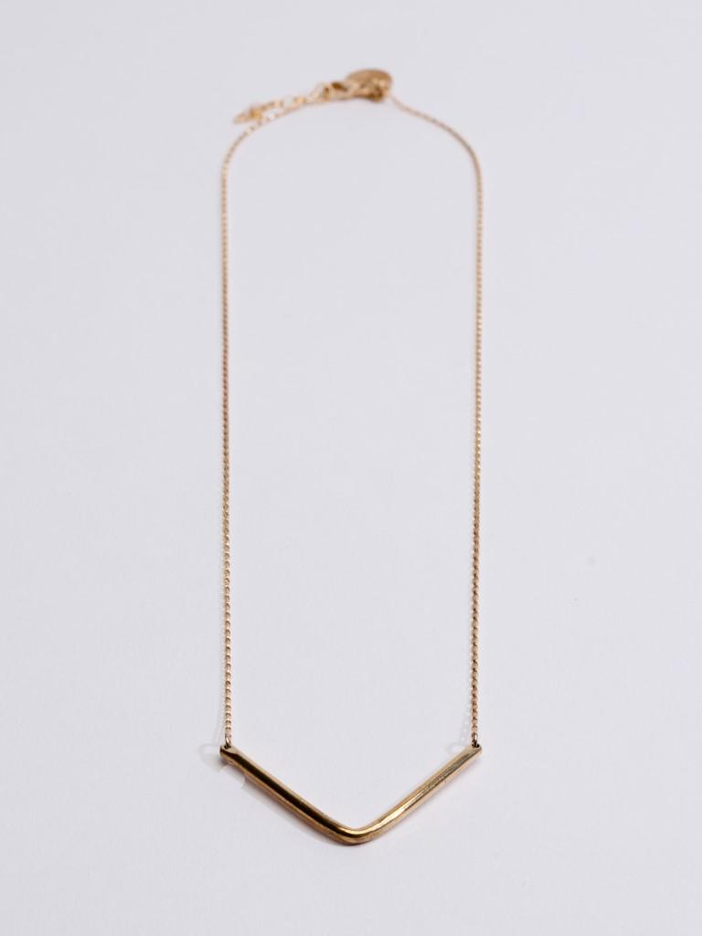A delicate gold Tribe Alive necklace with an angular geometric pendant against a white background