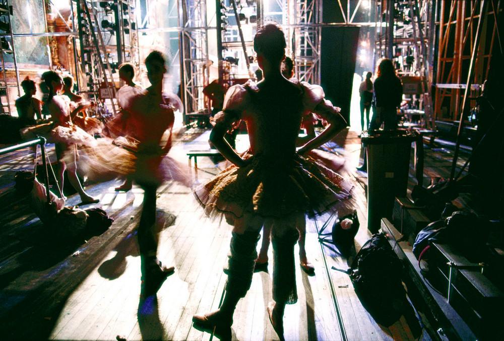 Ballerinas in tutus backstage among scaffolding and backlight