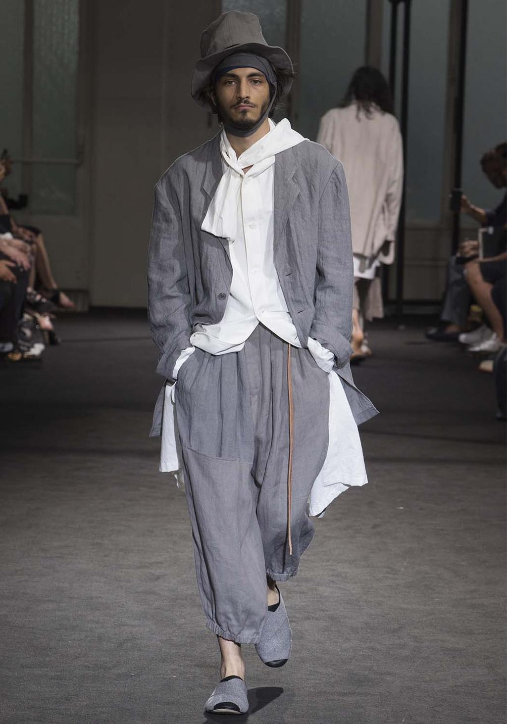 A man in a grey linen suit, white shirt and hat on the runway