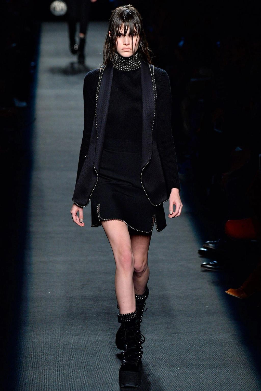 An Alexander Wang show: a black jacket and skirt with metallic detailing on a dark runway