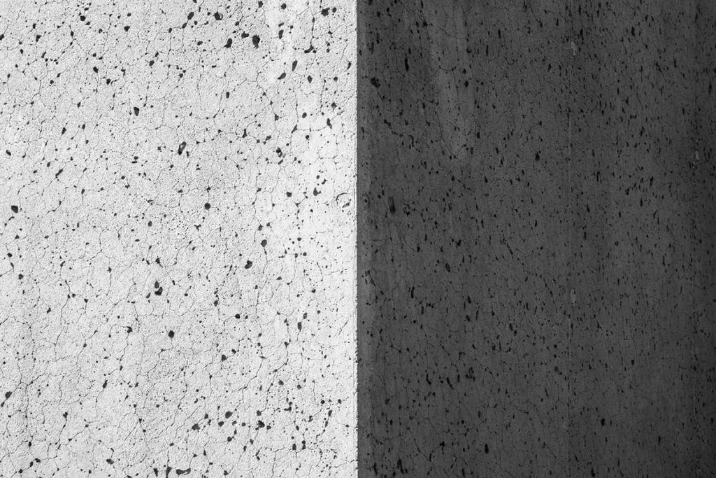 The texture of a concrete wall with a porous surface at the boundary of light and shadow