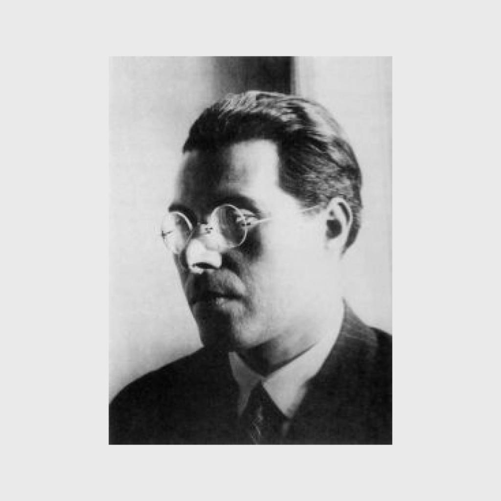 Чёрно-белый портрет молодого мужчины в круглых очках, профильно повёрнутого к свету