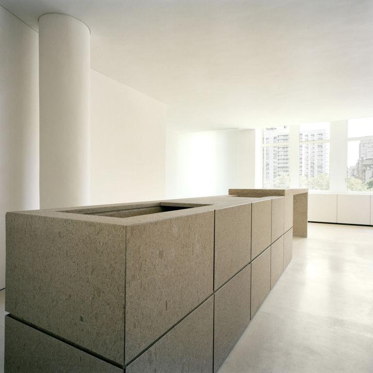 A long stone counter of large blocks set beside a window overlooking city high-rises