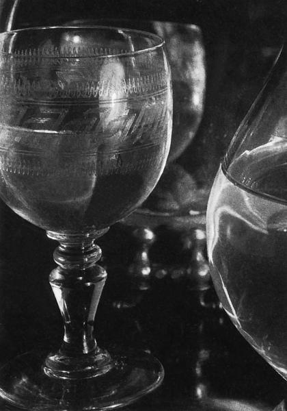 A still life with faceted glass tumblers and a carafe in backlight