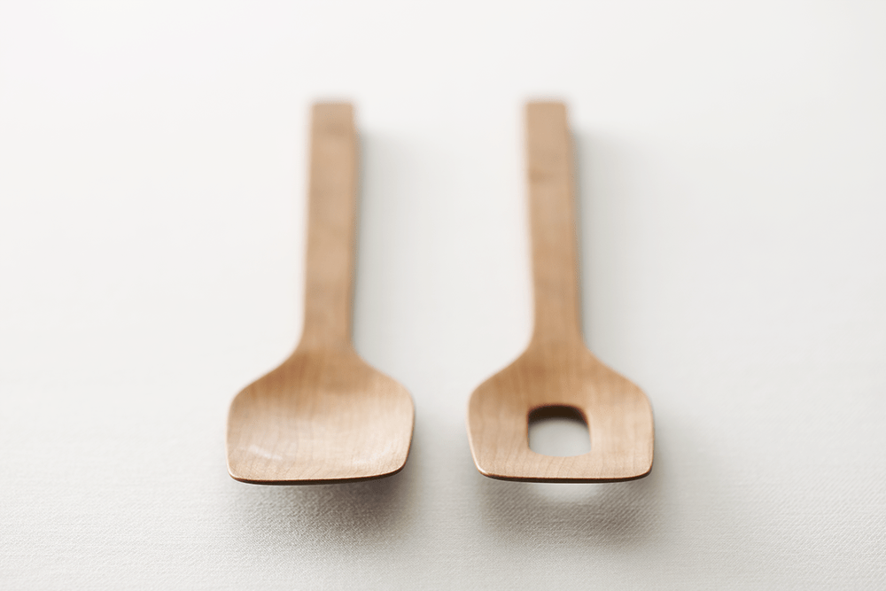 Two wooden spatulas in close-up, one with a rectangular slot