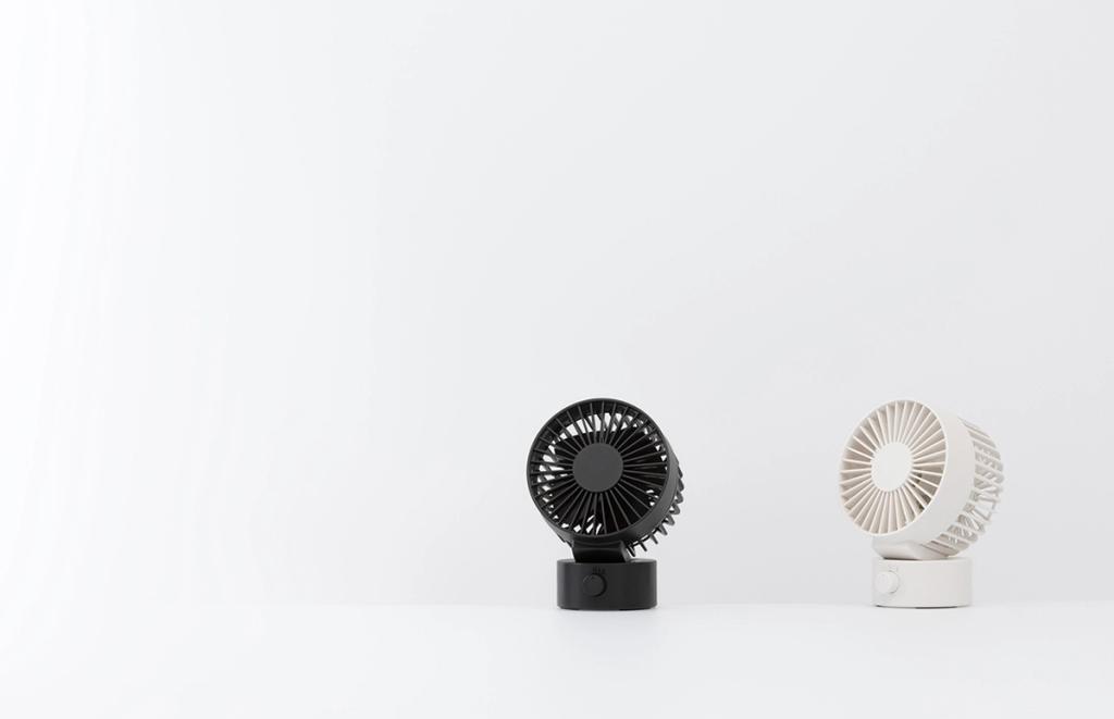 Two desktop fans, one black and one white, against a light background