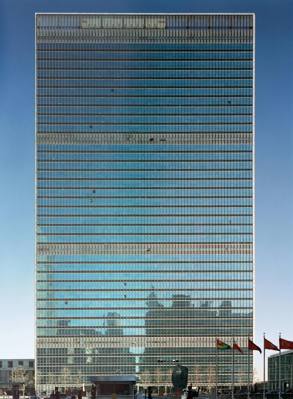 The façade of the UN Secretariat in New York — a glazed high-rise slab with flags at its base