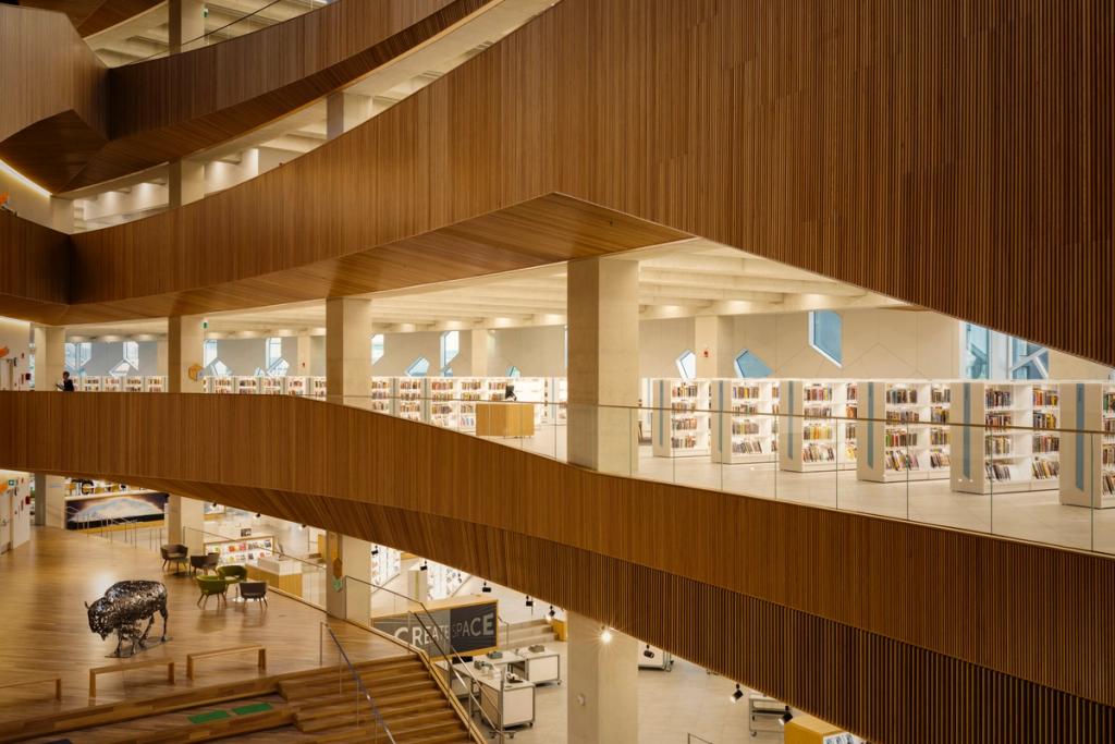 Wooden galleries with bookshelves and a metal bison sculpture in the atrium of the Calgary library