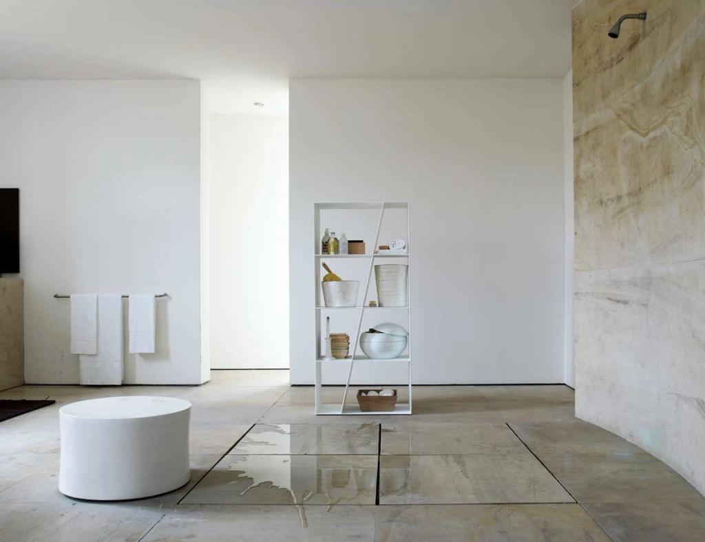 White X-shaped shelving unit in a minimalist bathroom with bath accessories