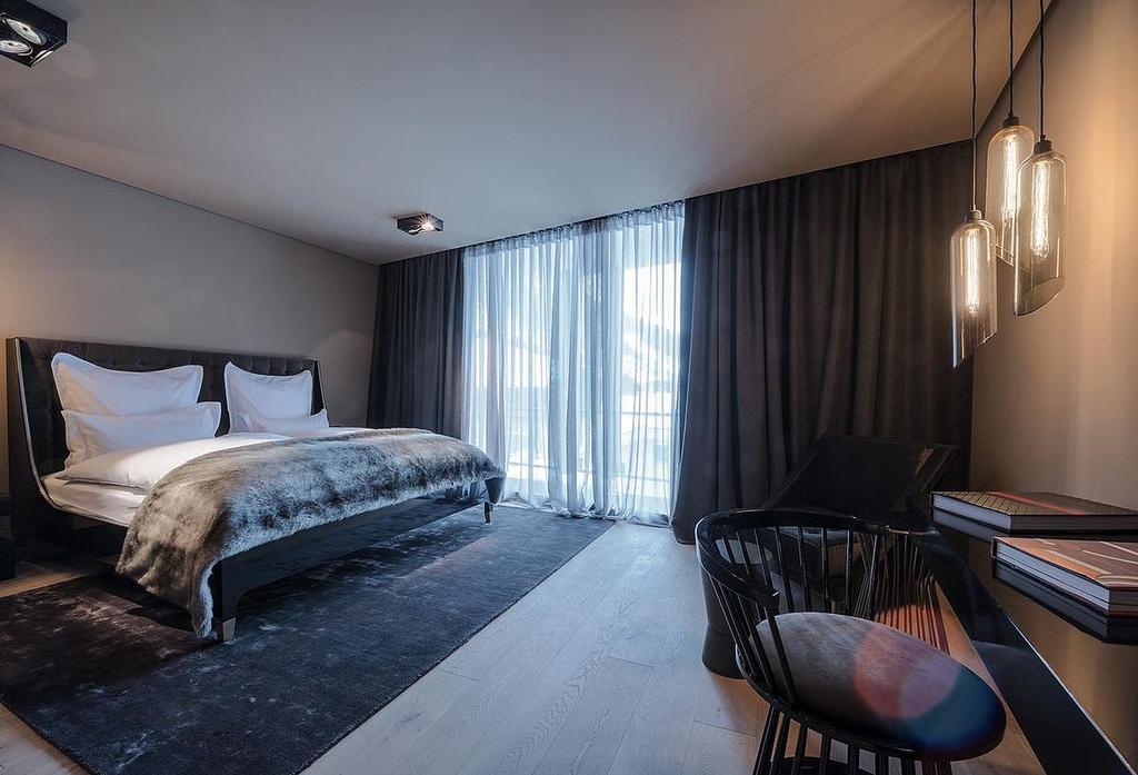 A dark Hotel Zhero room with a bed, a fur throw and pendant lights