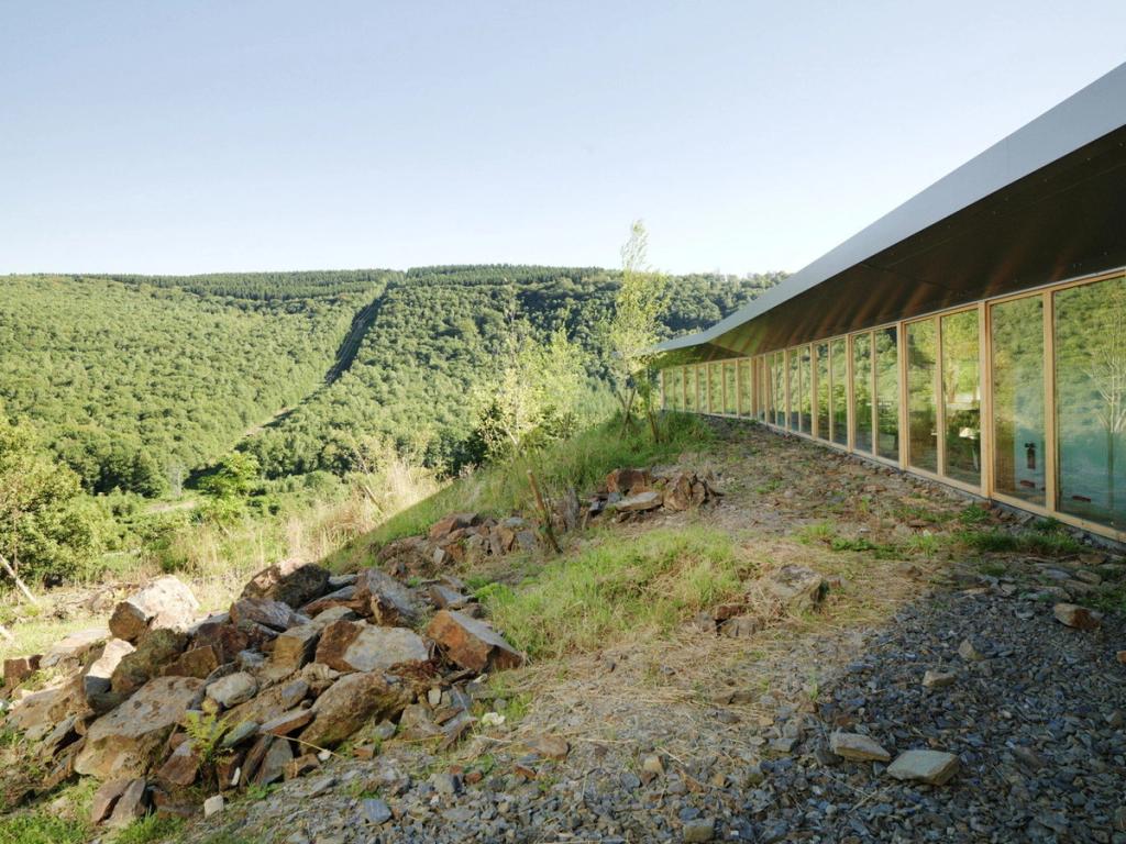 The glazed façade of Jean Moulin School running along the slope, with views over a wooded valley