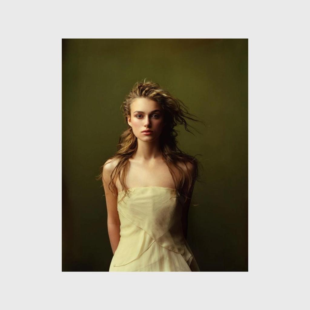 A colour portrait of a young woman with tousled hair in a cream dress against a green background
