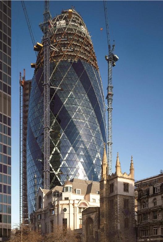 30 St Mary Axe under construction, its latticed steel frame visible alongside cranes and a historic church nearby