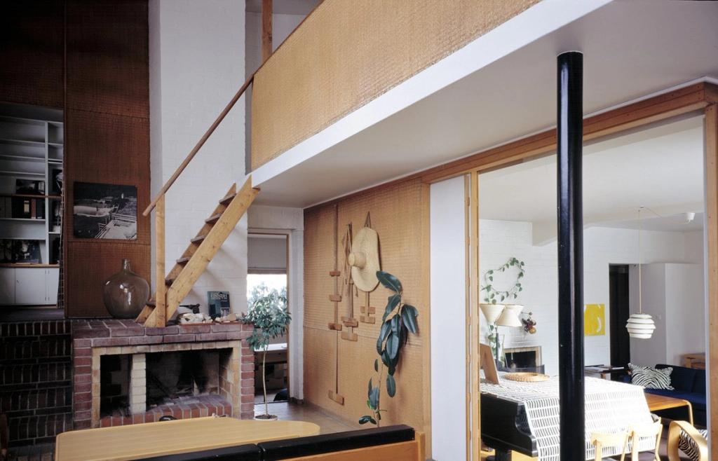 Interior of the Aalto house featuring a brick fireplace and a wooden staircase leading to a mezzanine