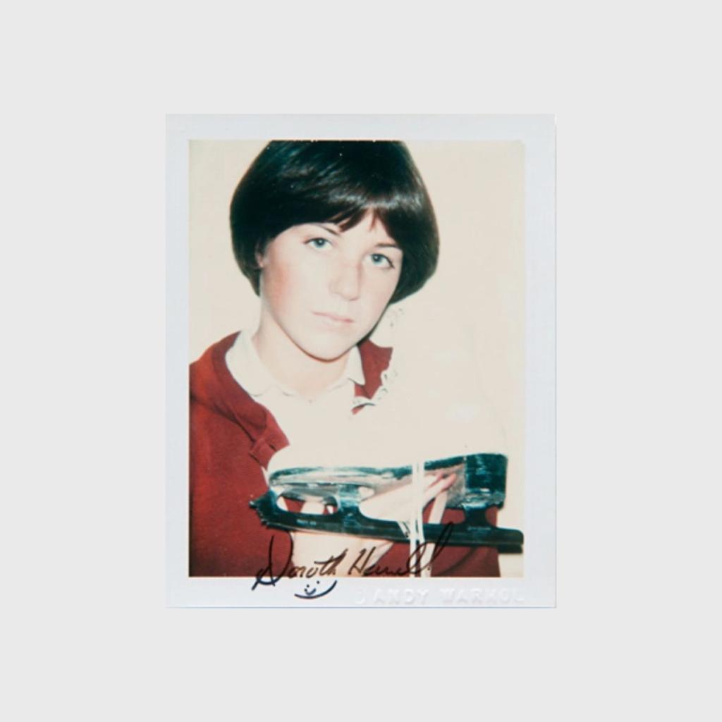 A Polaroid portrait of figure skater Dorothy Hamill holding a skate, signed with her autograph