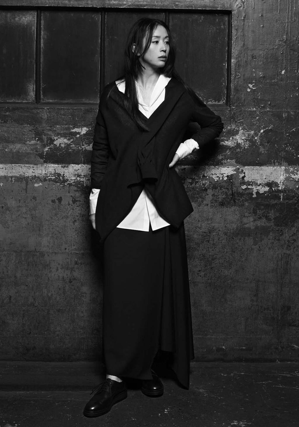 Black-and-white portrait of a woman in a black jacket and white shirt against a wall