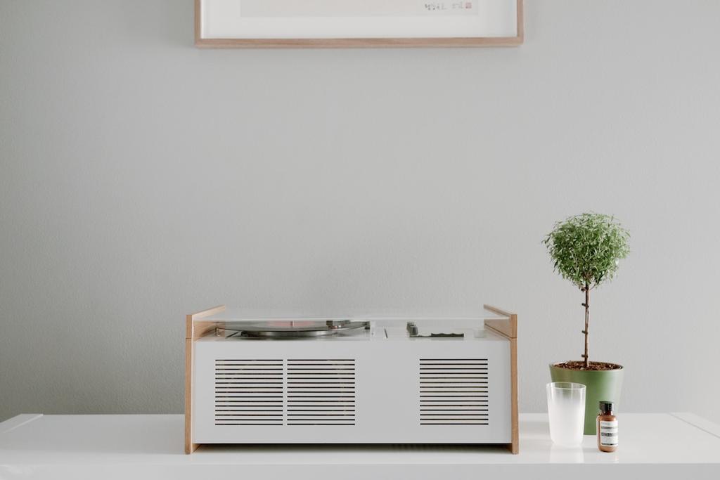 A white Braun SK55 turntable with wooden side panels on a shelf against a wall