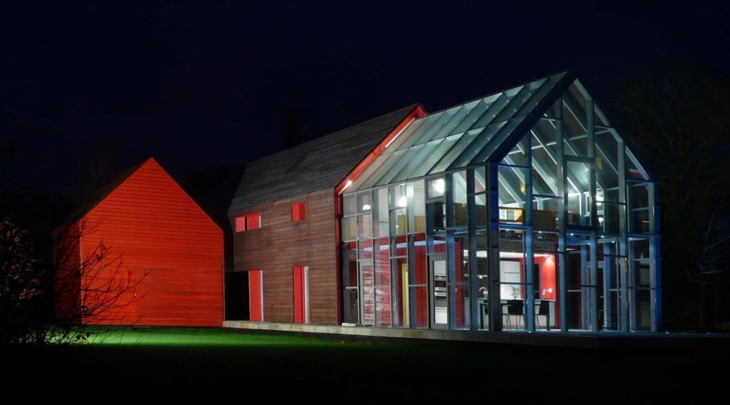 The glass volume of the dRMM Sliding House lit from within at night