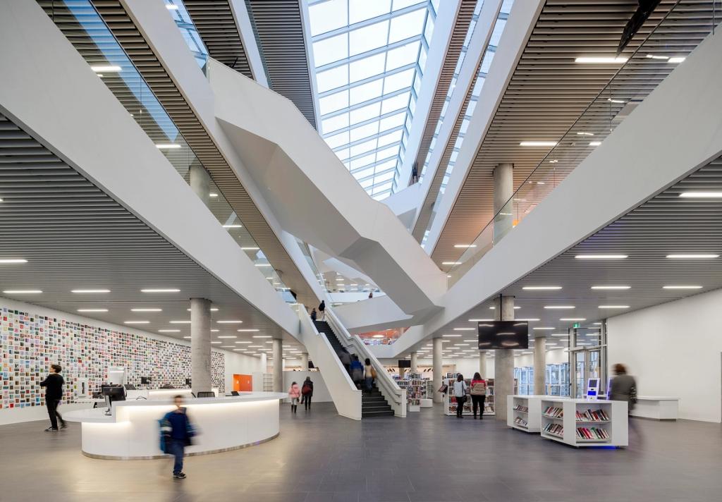 The spacious white lobby of the Halifax library with a circular service desk and an angular central staircase