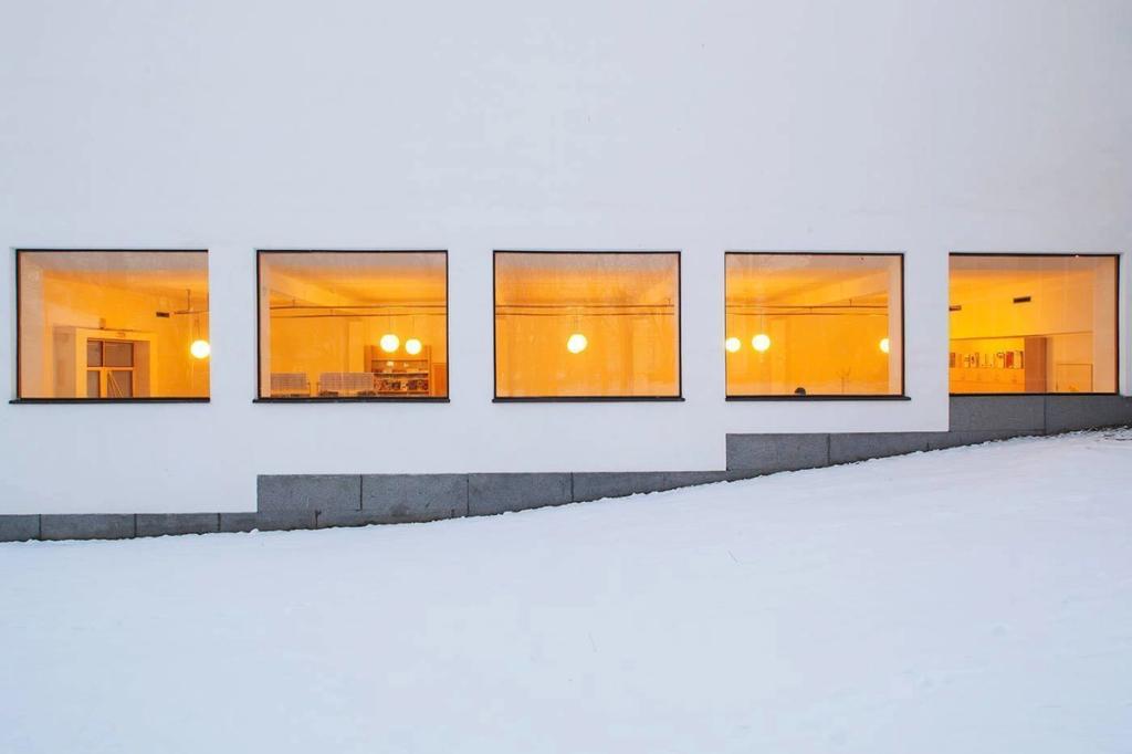 The façade of the Viipuri Library in winter, a row of windows glowing with warm orange light