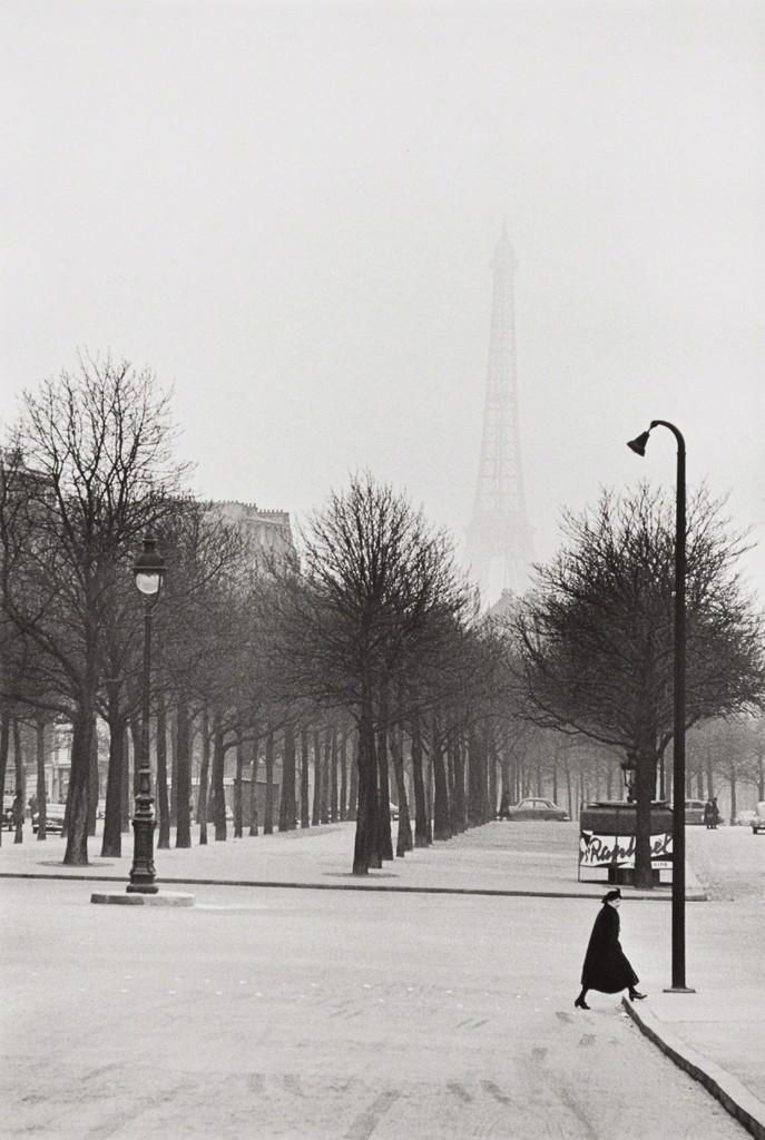 A wintry, fog-wrapped Paris: a solitary figure crosses an avenue, the Eiffel Tower visible on the horizon
