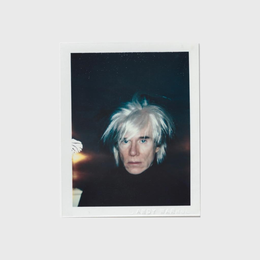 Andy Warhol's Polaroid self-portrait wearing a tousled blond wig and a dark sweater