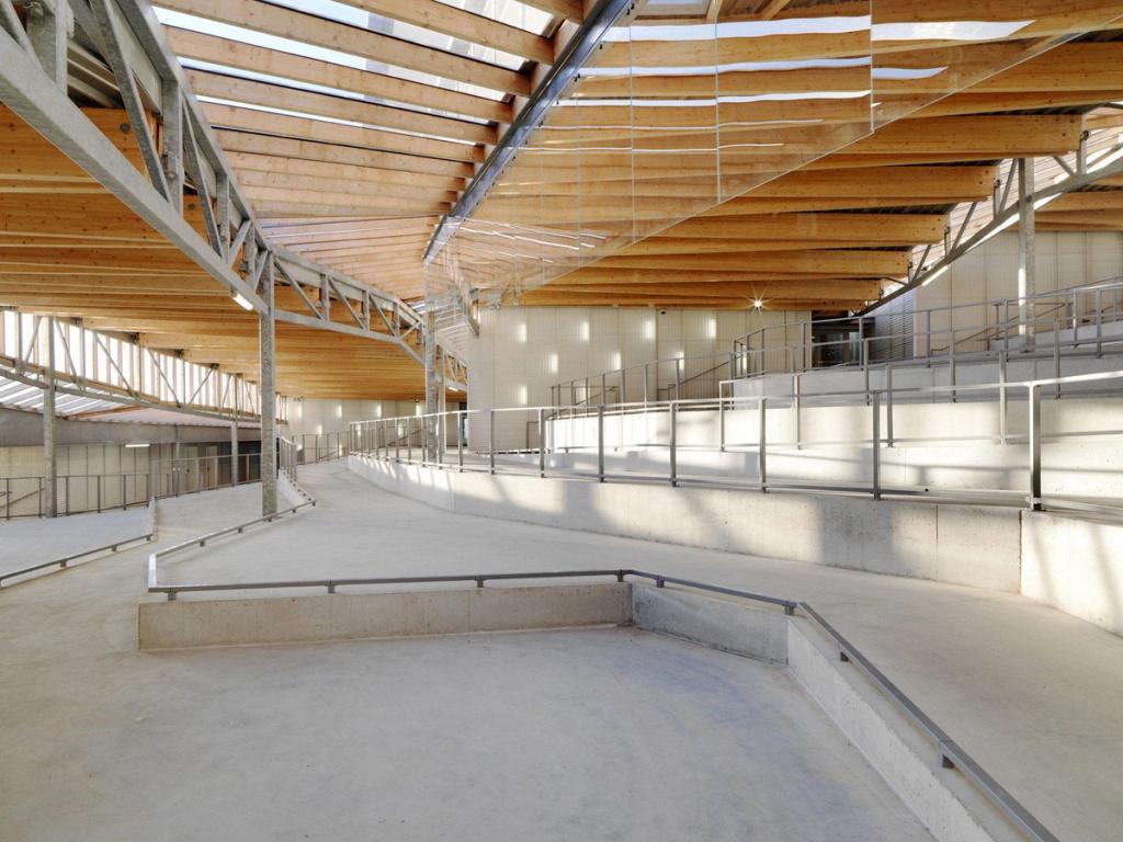 The sports hall of Jean Moulin School, with wooden roof trusses and concrete spectator stands