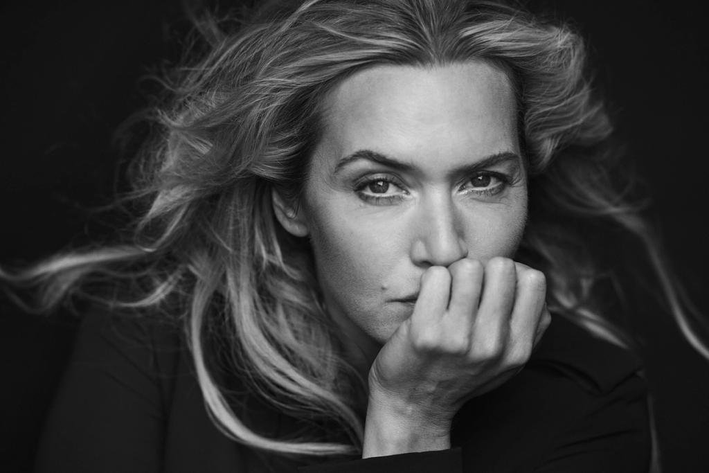 Black-and-white portrait of a fair-haired woman pressing her fist to her lips