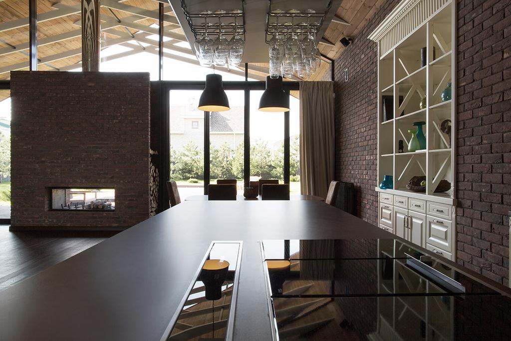 Dining room with brick walls, a long dark table and a white built-in sideboard with glass shelves