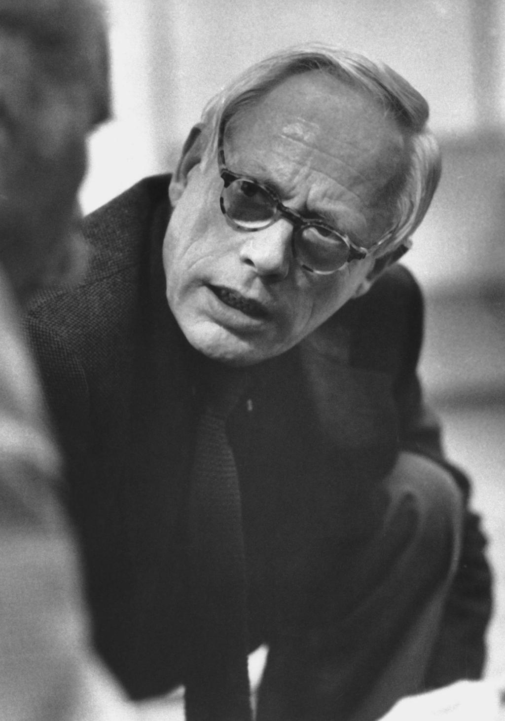 A black-and-white portrait of the elderly designer Dieter Rams wearing glasses