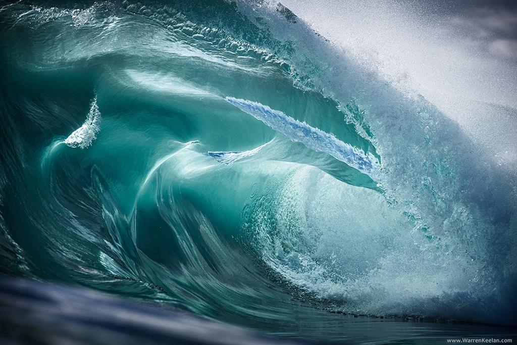 Close-up of a curling emerald wave with smooth, folded water surfaces