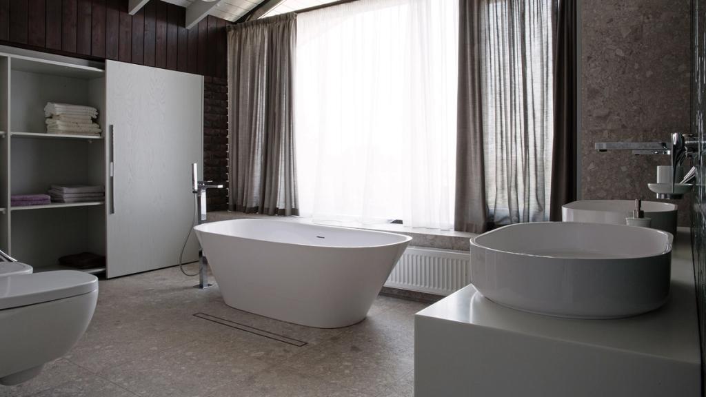 A bathroom with a freestanding bath, round basins and a large curtained window