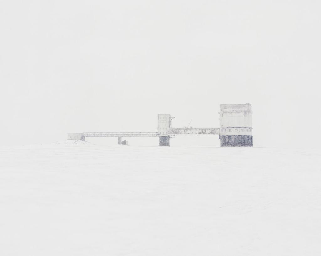 An abandoned hydraulic engineering facility with a viaduct and support pillars amid a snow-covered plain