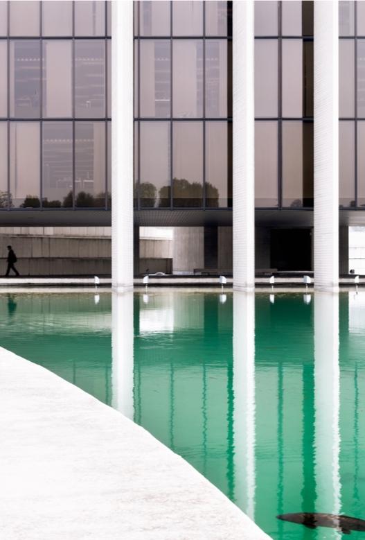 The glass facade of the Mondadori building with reflections of neighbouring structures in the water