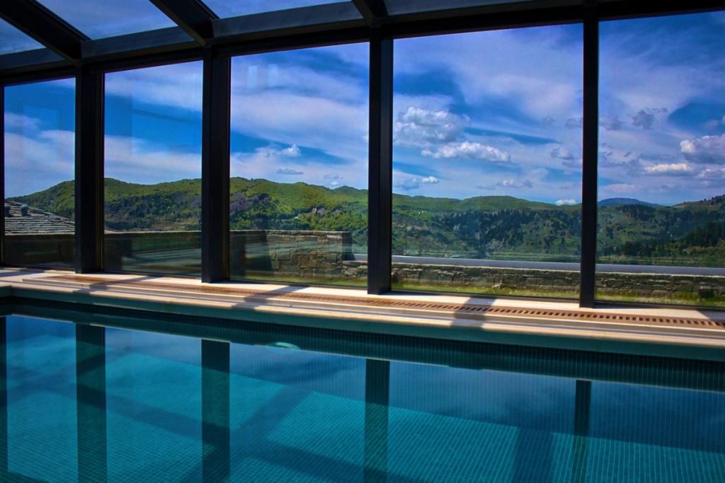 Grand Forest Metsovo indoor pool with a panoramic window facing the green hills