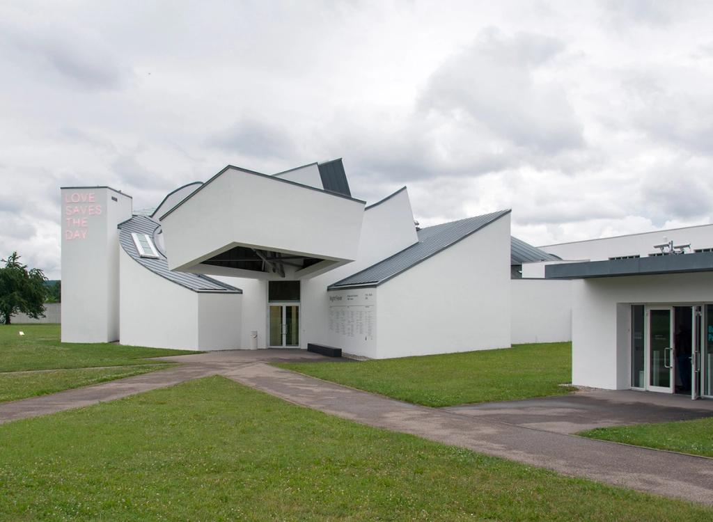 Белый Музей дизайна Vitra Фрэнка Гери с входом и неоновой надписью на башне