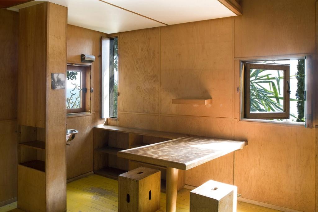 The plywood interior of the Cabanon with a table, cube-shaped stools and small windows