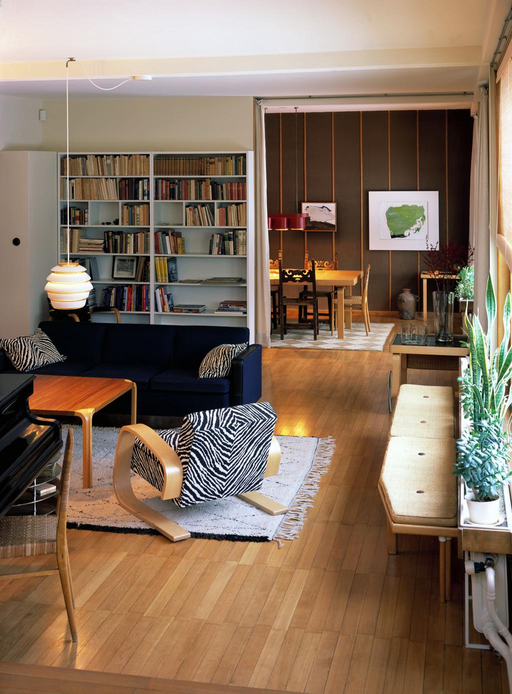 The living room of the Aalto house with a bookshelf, a blue sofa and a Paimio chair with a zebra-print cushion