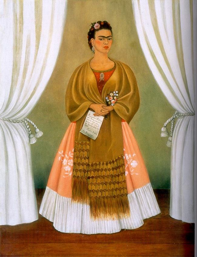 Frida Kahlo's self-portrait dedicated to Leon Trotsky: the artist in a brown shawl and pink skirt, standing between white curtains.