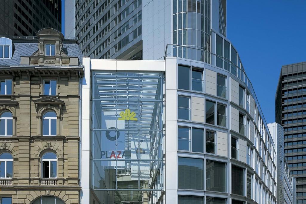 The glass walkway of the Commerzbank Tower alongside an old stone building