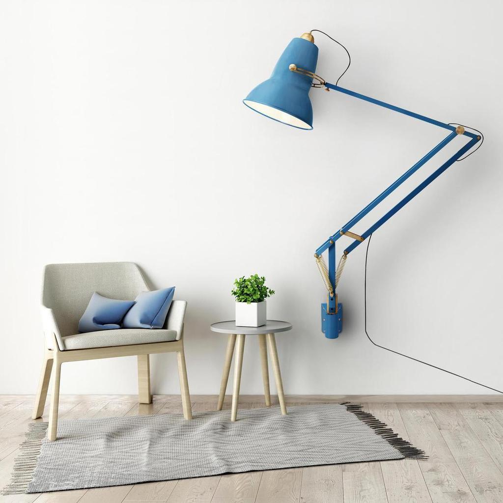 Большая синяя настенная лампа Anglepoise над креслом и журнальным столиком с растением