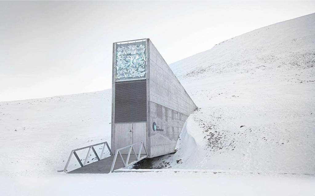 The concrete entrance portal of the seed vault, its glowing mosaic set into the side of a white snow-covered hill