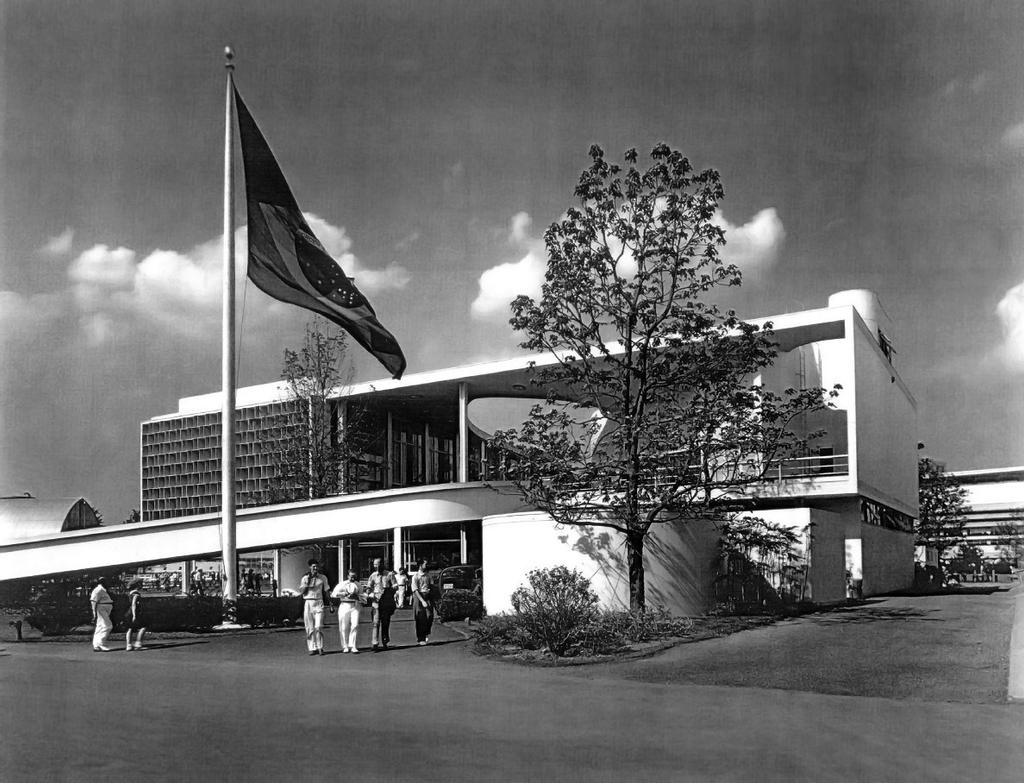 The Brazil Pavilion at the World's Fair, its flag flying above the entrance, with visitors gathered outside