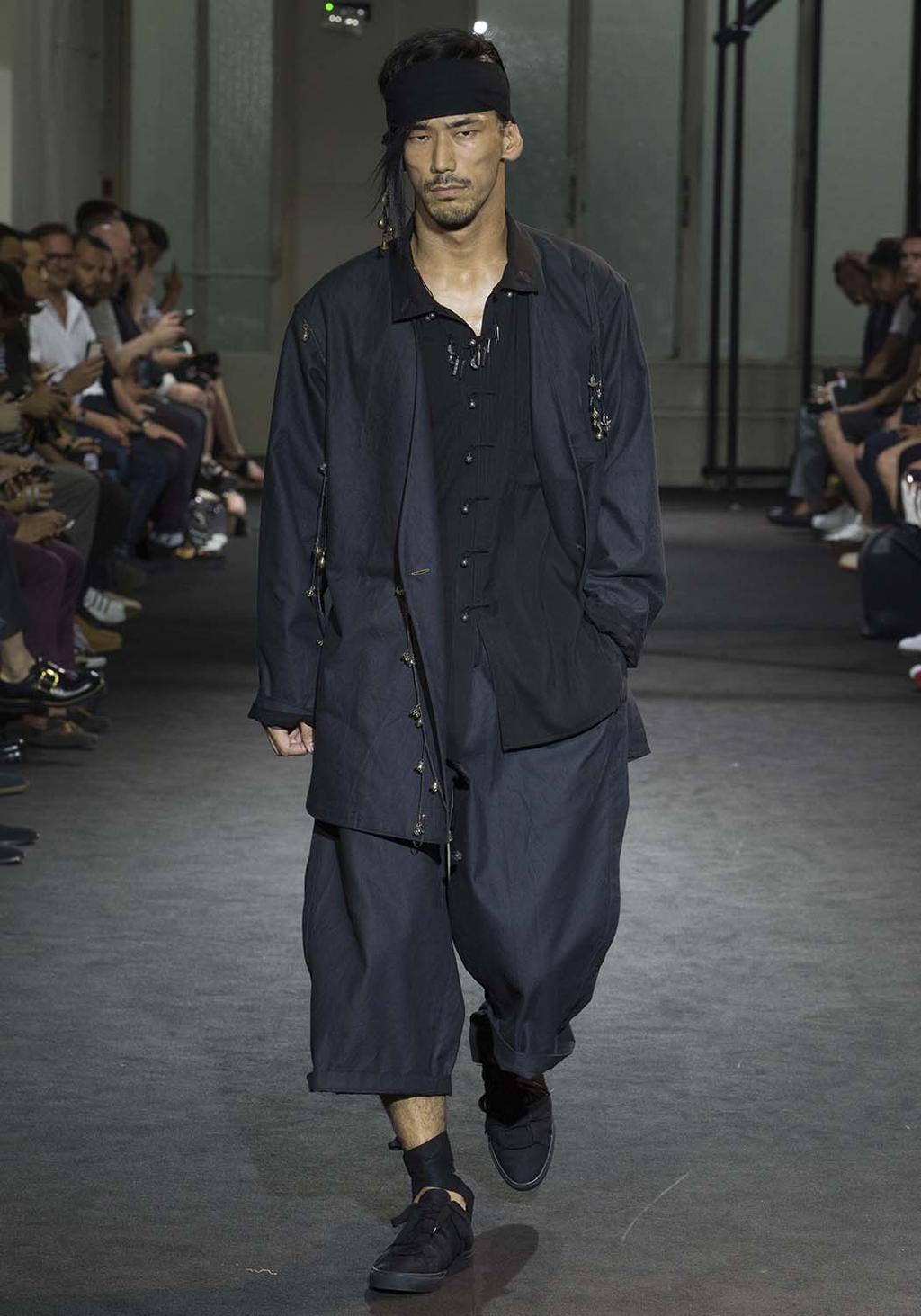 A man in a dark navy look with a bandana and wide trousers on the runway