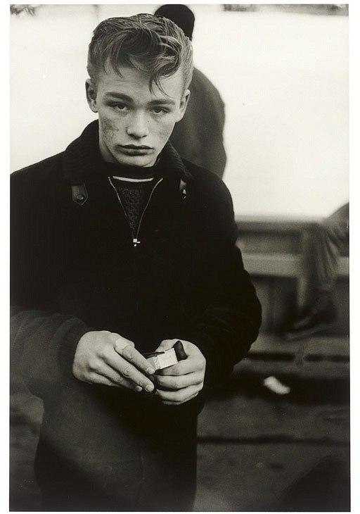 Portrait of a fair-haired young man in a dark coat with freckles, holding a box of matches