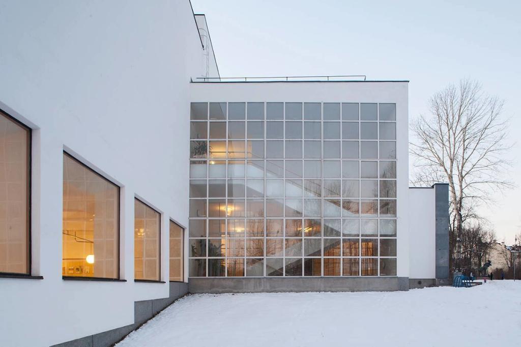 The façade of the Viipuri Library with a large grid-pattern glazed wall, snow surrounding the building