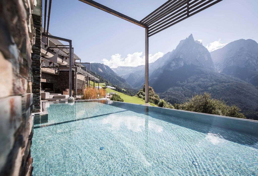 A pool with turquoise water and a view of the Schlern rock peak in the Dolomites